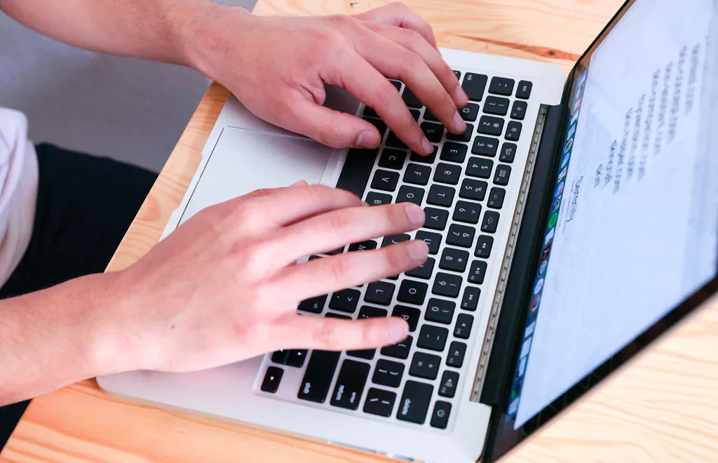Hands typing on a laptop.