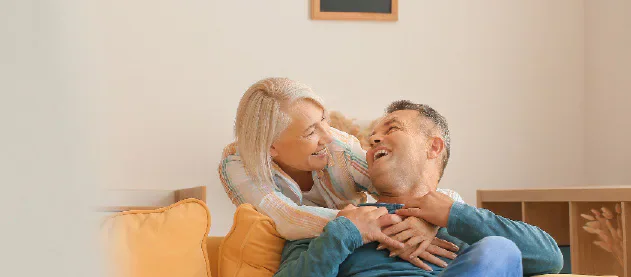 An older couple laughing together on a sofa.
