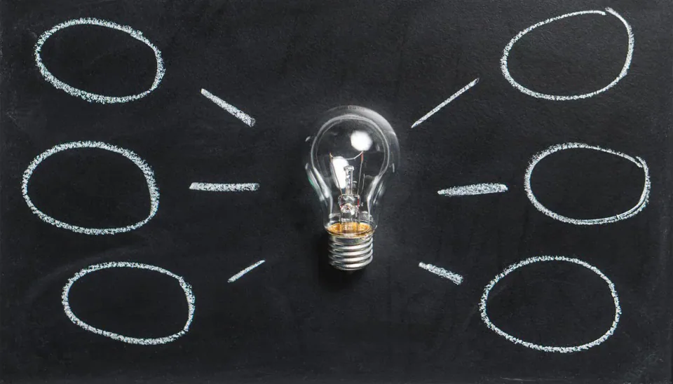 A light bulb linked to chalk circles on a blackboard.