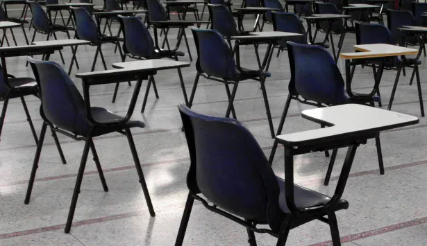 Rows of empty classroom chairs with writing tablets.
