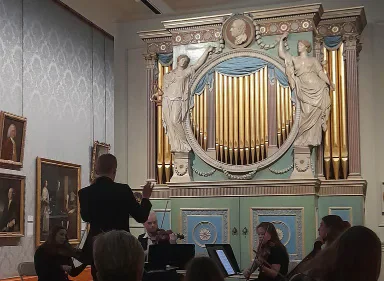 Museum visitors looking at a decorative organ.