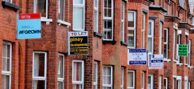 A row of brick terraced houses with several letting-agent signs.