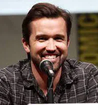 Actor Rob McElhenney smiling while speaking into a microphone.