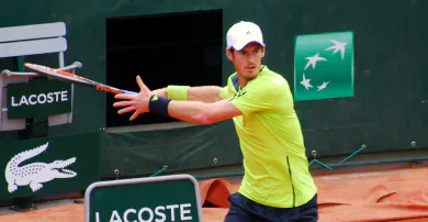 Andy Murray holding his racket with both hands on a clay tennis court.