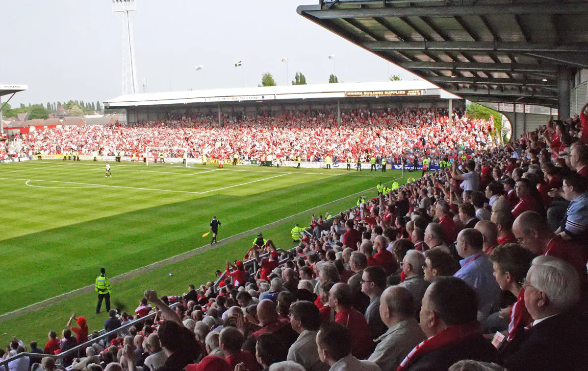 Supporters watching a Wrexham football match from a packed stand at the Racecourse Ground.
