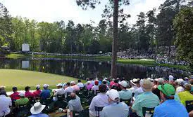 Spectators watching golfers beside a pond at Augusta National Golf Club.
