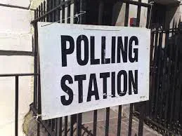 A polling station sign attached to black railings.