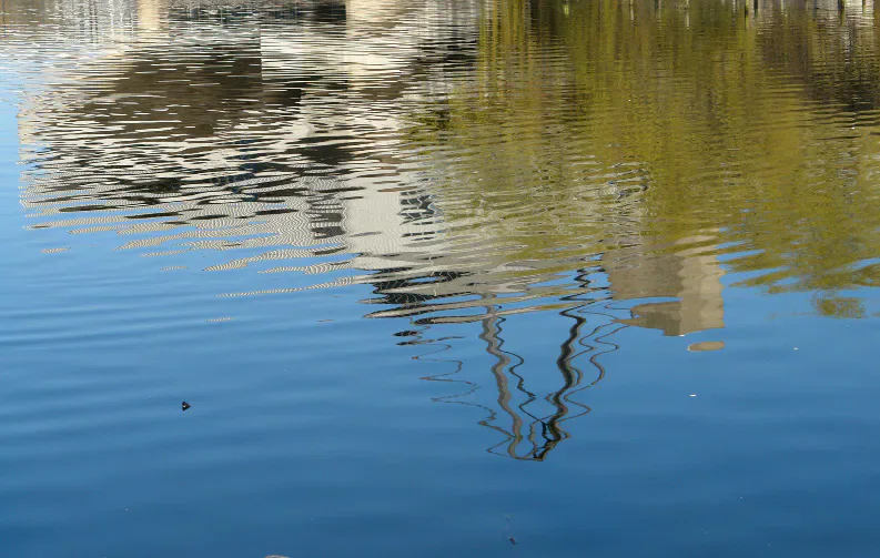 Rippling water reflecting a building and trees