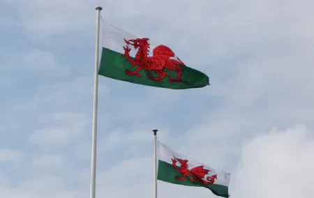 Two Welsh flags flying against a cloudy sky
