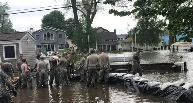 National Guard personnel working beside sandbags in a flooded residential street