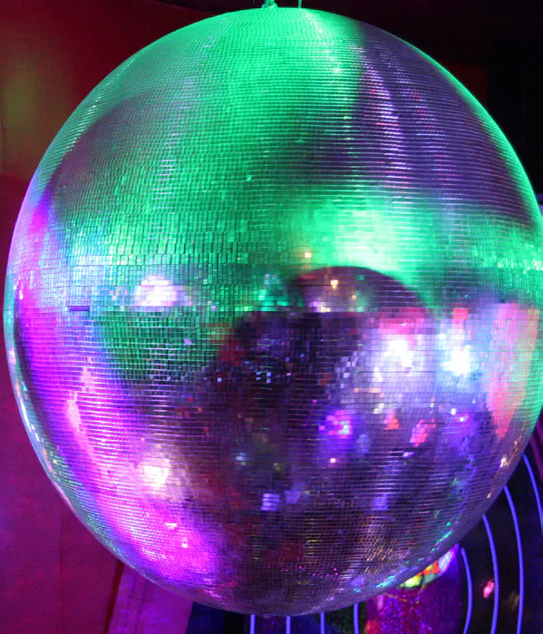 A disco ball lit green, purple and pink