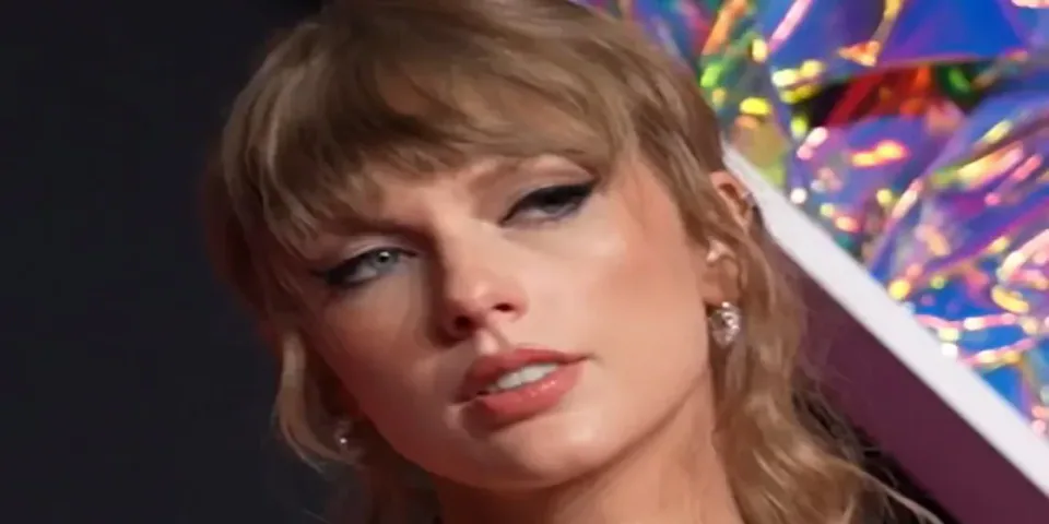 Taylor Swift wearing a black dress and layered necklaces