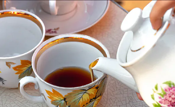 Tea being poured from a teapot into a patterned cup