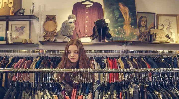 Shopper browsing rails of clothing in a vintage shop