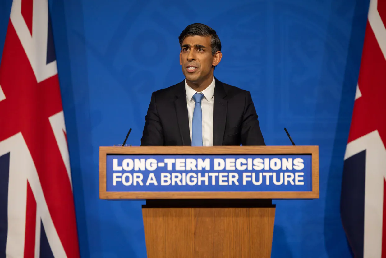Rishi Sunak speaking at a lectern between Union flags