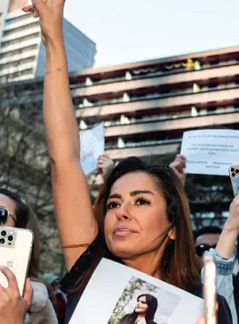 A protester raising one arm while holding a printed photograph of a woman