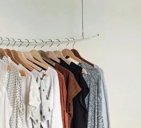 Neutral-coloured clothes hanging on wooden hangers from a rail