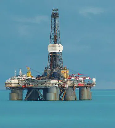 An offshore oil drilling platform standing in blue sea