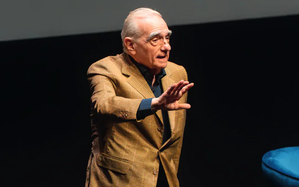 Martin Scorsese speaking on stage with one hand raised