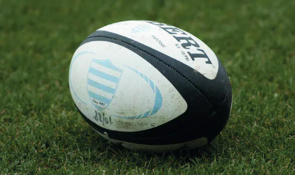 A black and white Gilbert rugby ball resting on grass