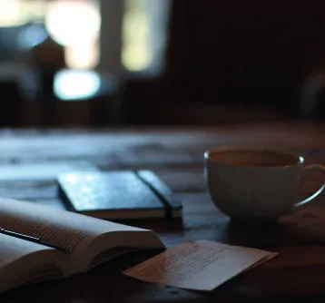 Coffee cup, open book and notebook on a table