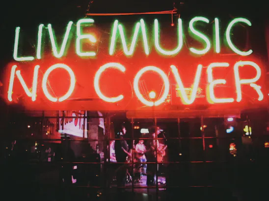 Neon sign reading LIVE MUSIC NO COVER above a bar
