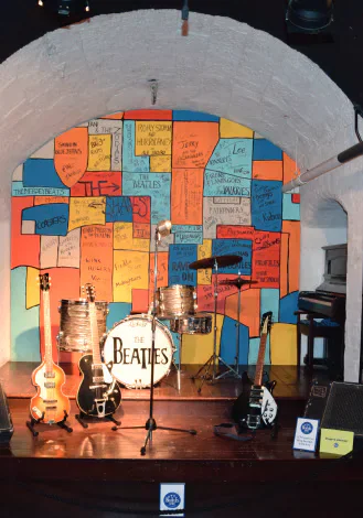 Beatles instruments displayed before a wall of colourful notes