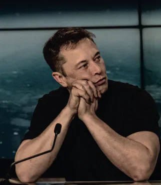 Elon Musk seated at a microphone