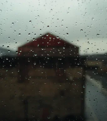 Raindrops on a window with a blurred building beyond