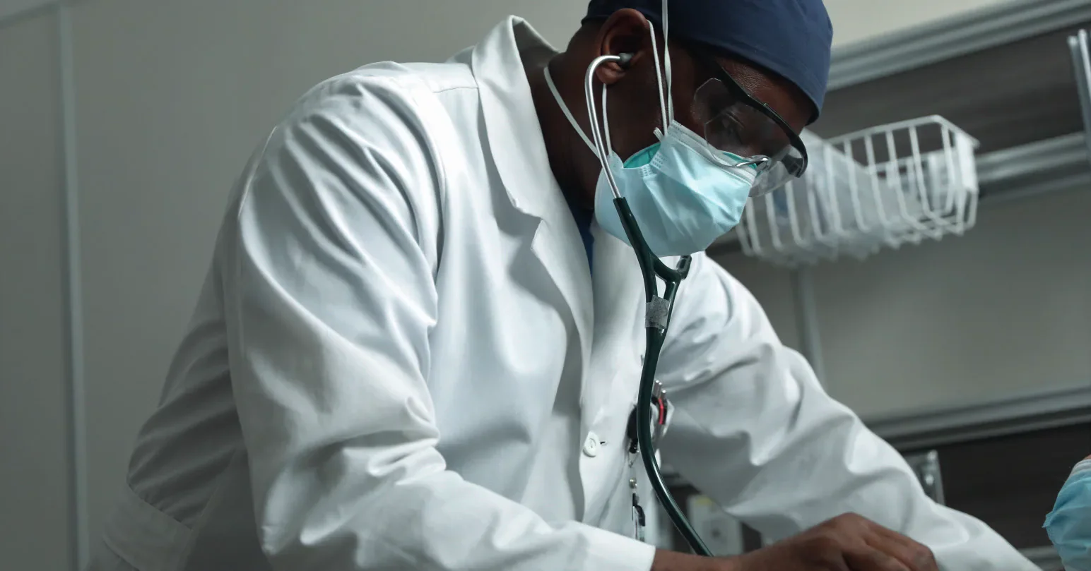 Masked clinician using a stethoscope
