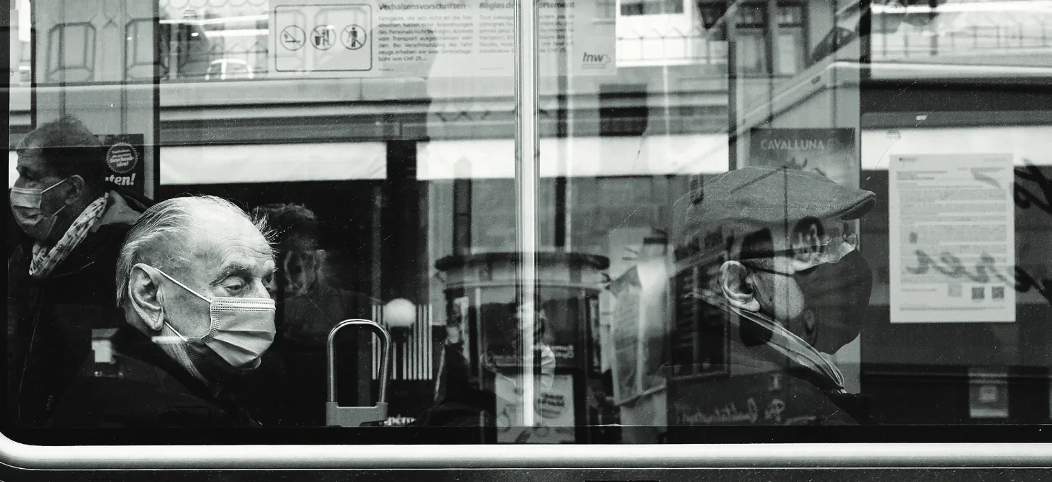 Two people wearing face masks seen through a window.