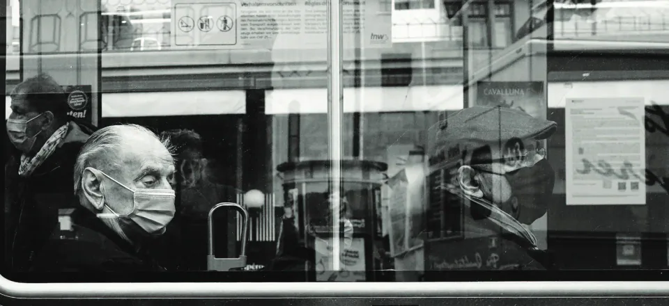 Two people wearing face masks seen through a window.