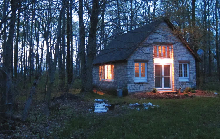 A lit house in woods at night.
