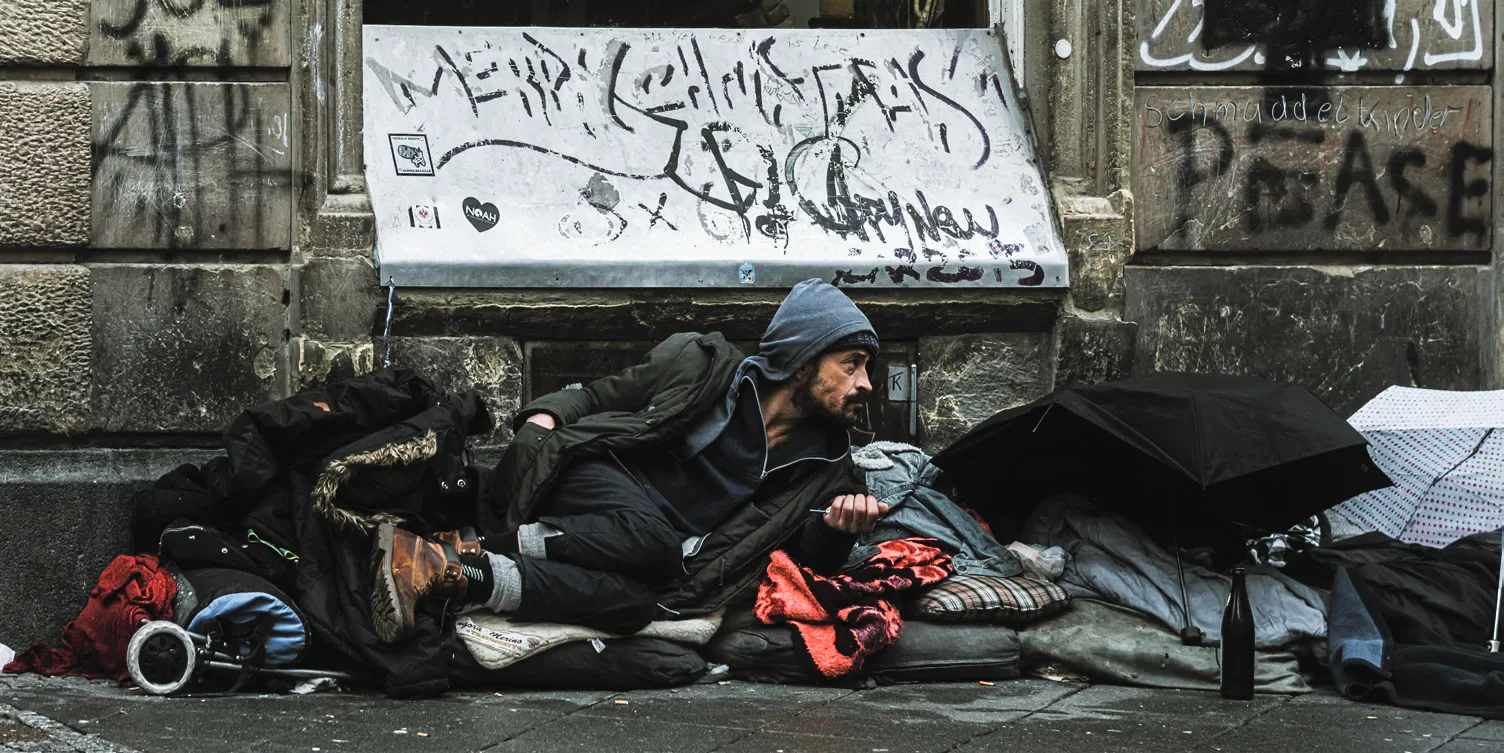 A person sleeping rough beneath graffiti.