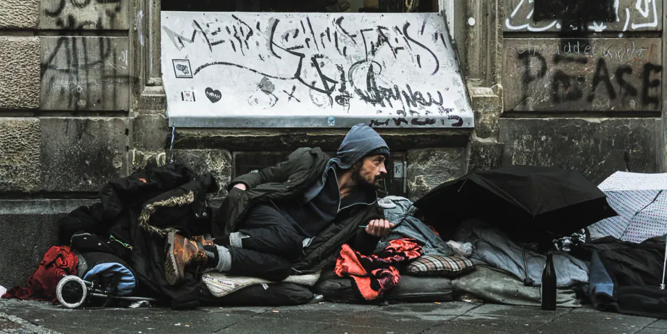A person sleeping rough beneath graffiti.