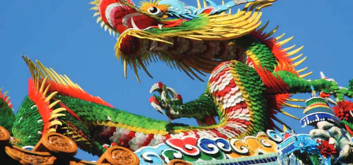 A colourful dragon decoration against a blue sky.