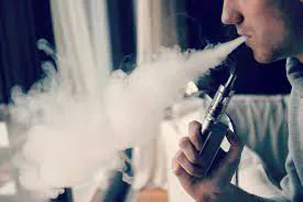 A person exhaling vapour while using an electronic cigarette.