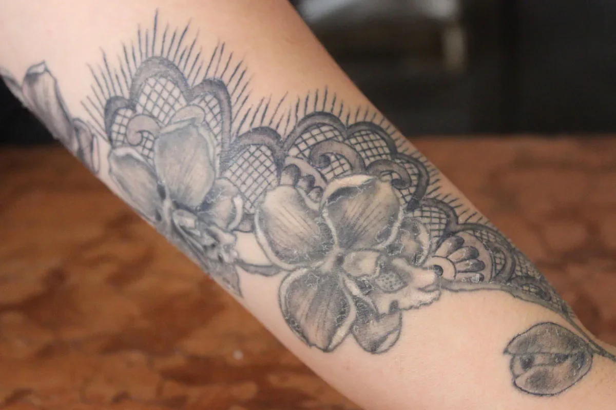 A floral tattoo with lace-like details on a person’s forearm.