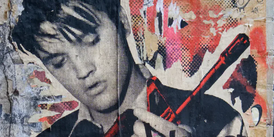 Layered street art depicting a young woman holding a red book.