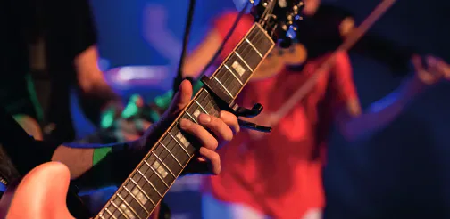 Close-up of a musician playing an electric guitar on stage.