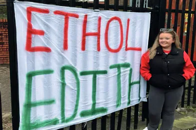 Catrin Edith stands beside a handmade EITHOL EDITH election banner.