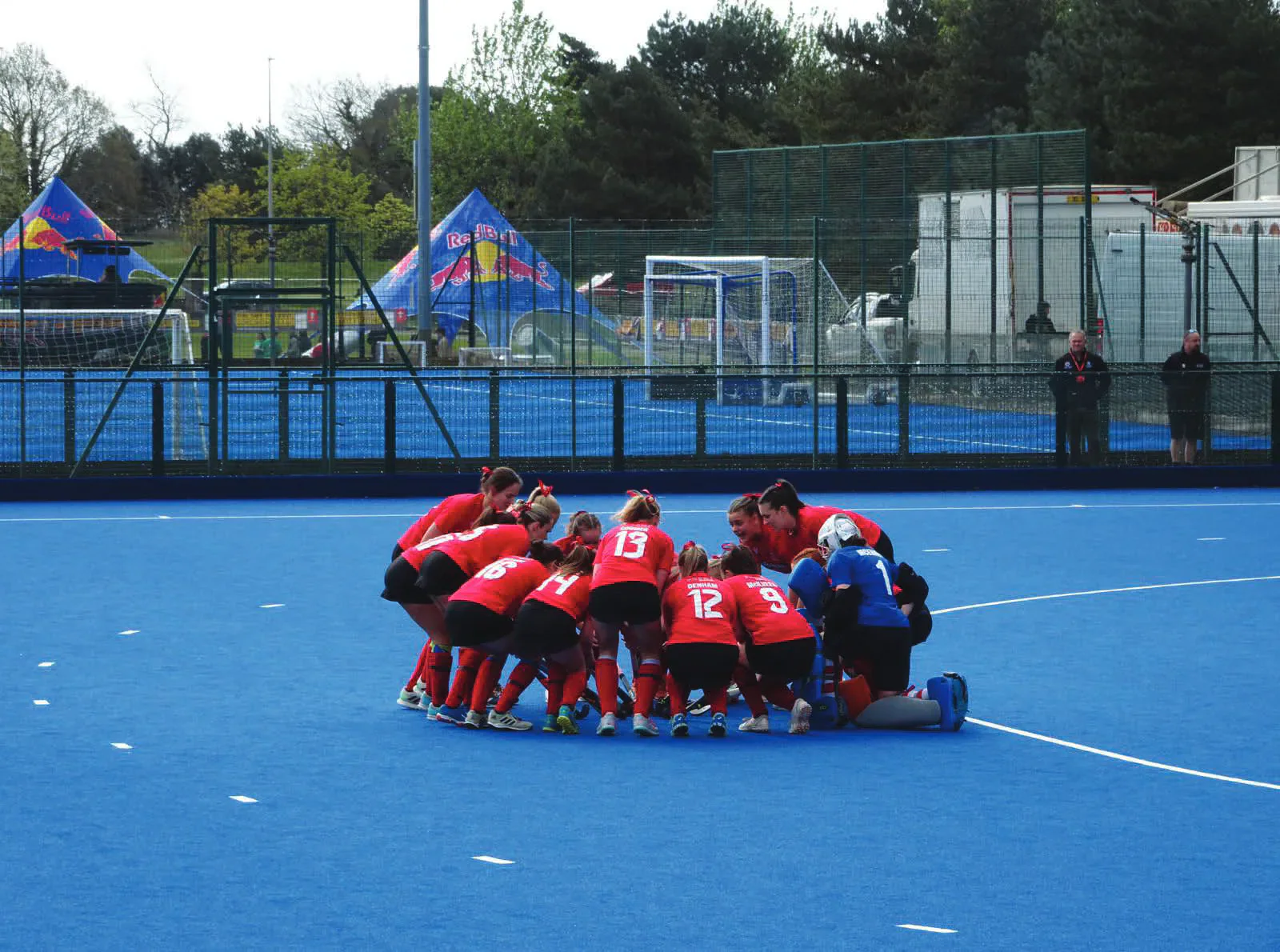 Cardiff women’s hockey players in a huddle on the blue pitch