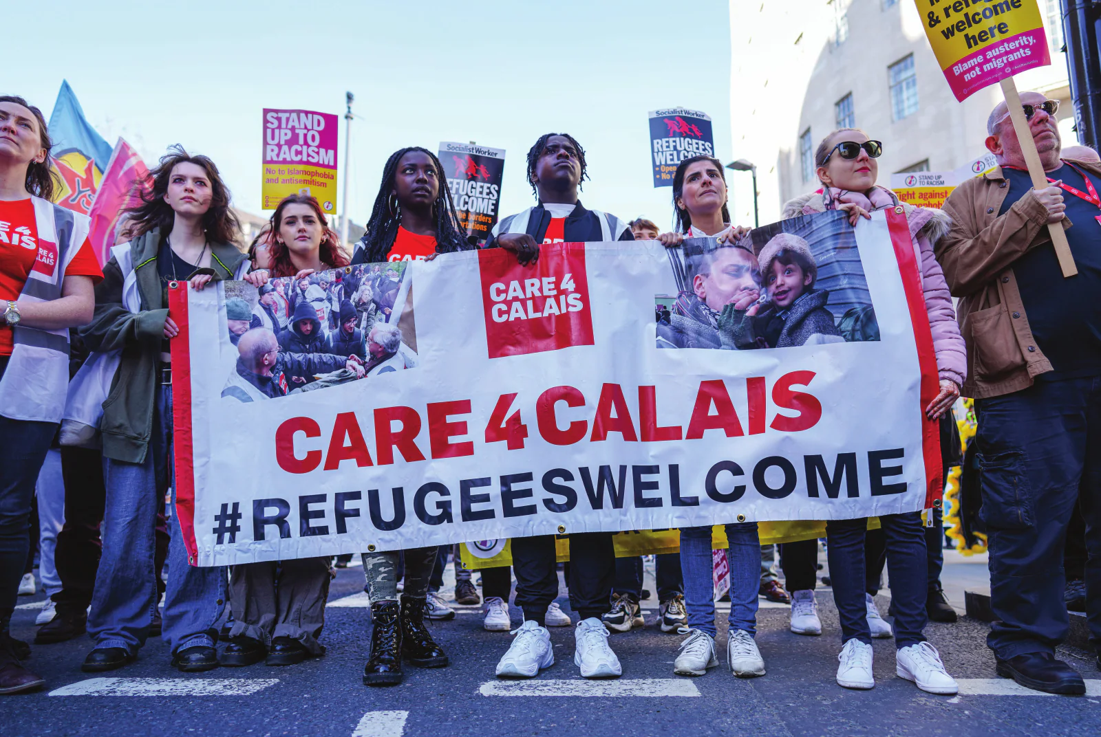 Care4Calais demonstrators holding a CARE 4 CALAIS #REFUGEESWELCOME banner