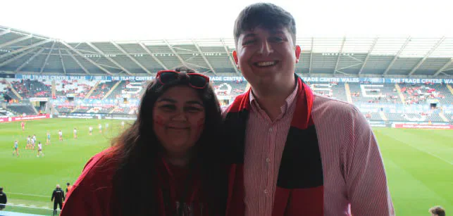 Two Cardiff student media members at a football ground