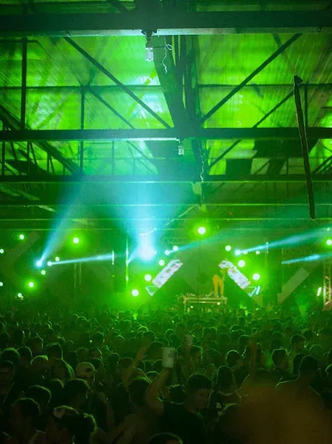 A concert crowd under vivid green stage lighting.