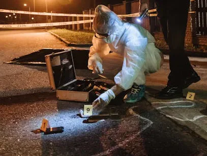 A forensic investigator examining evidence markers at night.