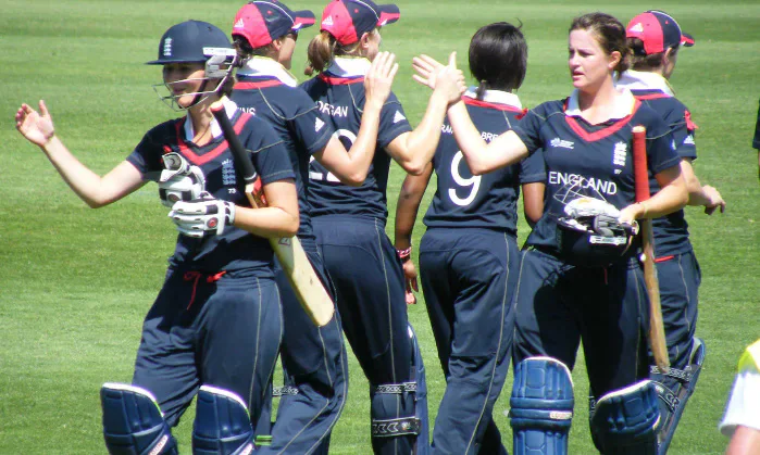 England women cricketers celebrating together on the field.