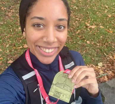Laila holding her Cardiff Half Marathon medal outdoors.