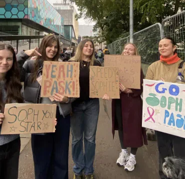 Supporters holding handmade signs for Sophie Pask beside the Cardiff Half Marathon route.