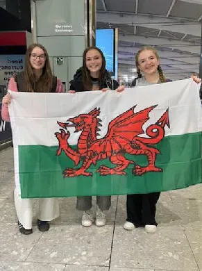 Tair myfyrwraig yn dal baner Cymru wrth deithio i Batagonia.